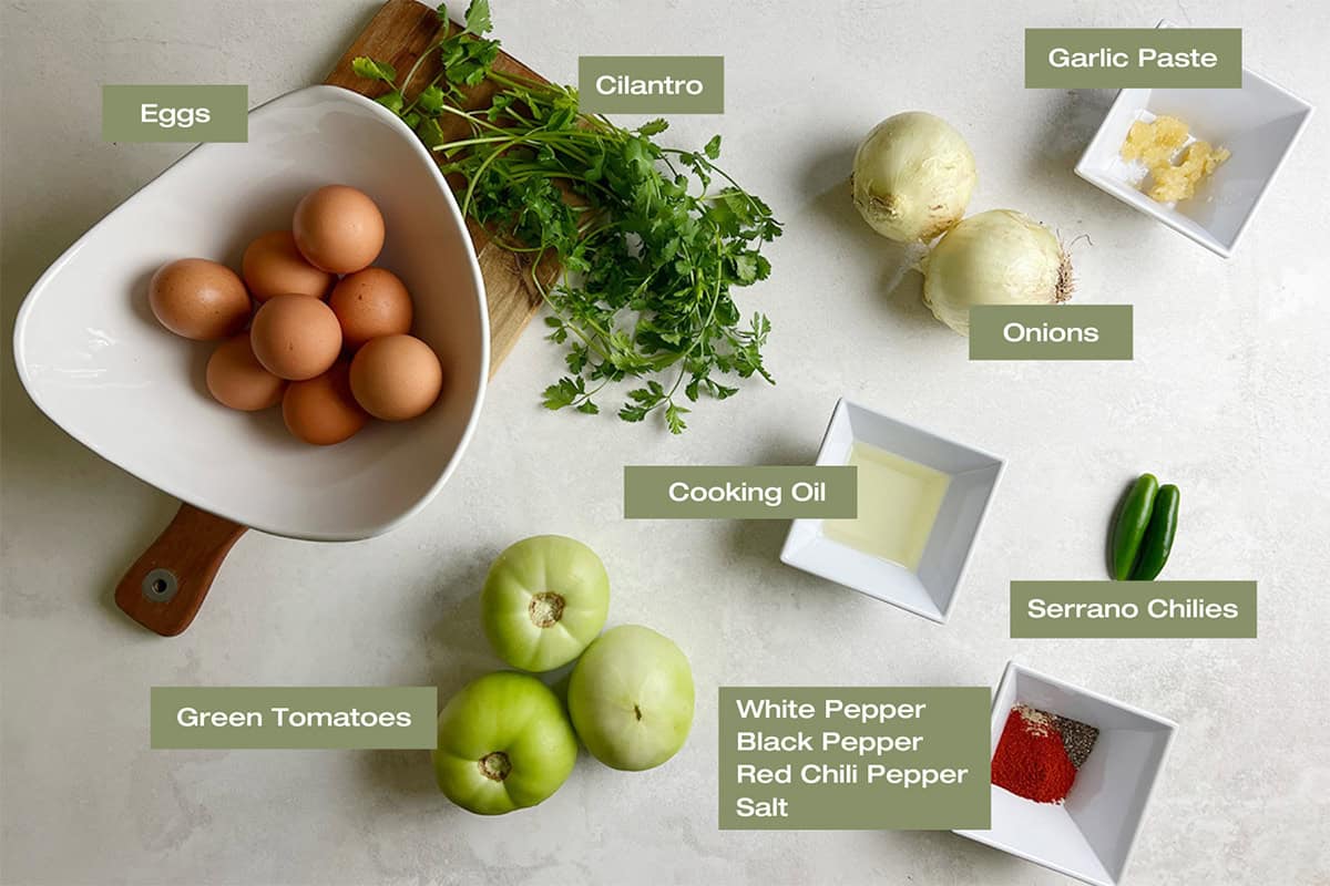 Ingredients to cook a n easy shakshuka recipe with green tomatoes are sitting in assorted containers on a kitchen counter.