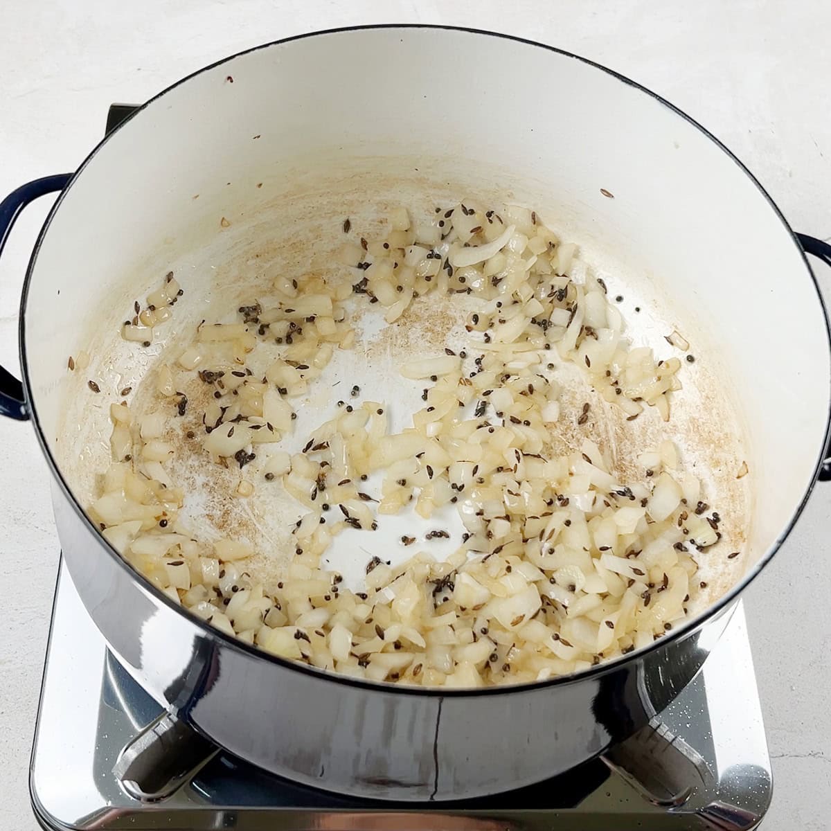whole spices and onions are being cooked for a curry base.