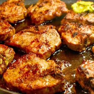 Pan seared lamb chops in a skillet accompanied with a homemade cilantro sauce.