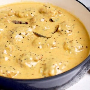 Kadhi recipe with pakora is served in a white and blue cooking pot.