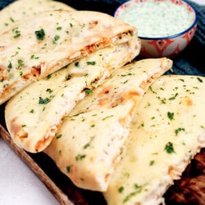 A leftover turkey recipe for naan is served on a dark wooden board.