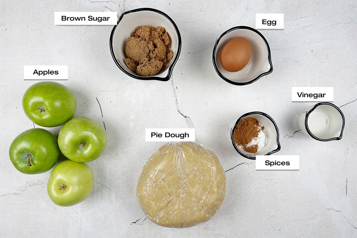 Ingredients for an apple galette recipe are laid out on a white kitchen counter.