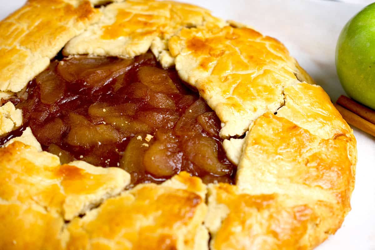 Apple galette recipe (with cooked filling) is served on a white platter.