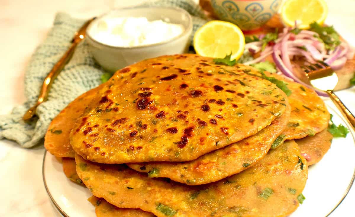 Cooked missi roti is plated and served with a side of plain yogurt.