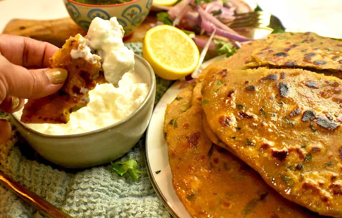 A chickpea flour flatbread is plated and served with yogurt, onions and limes.