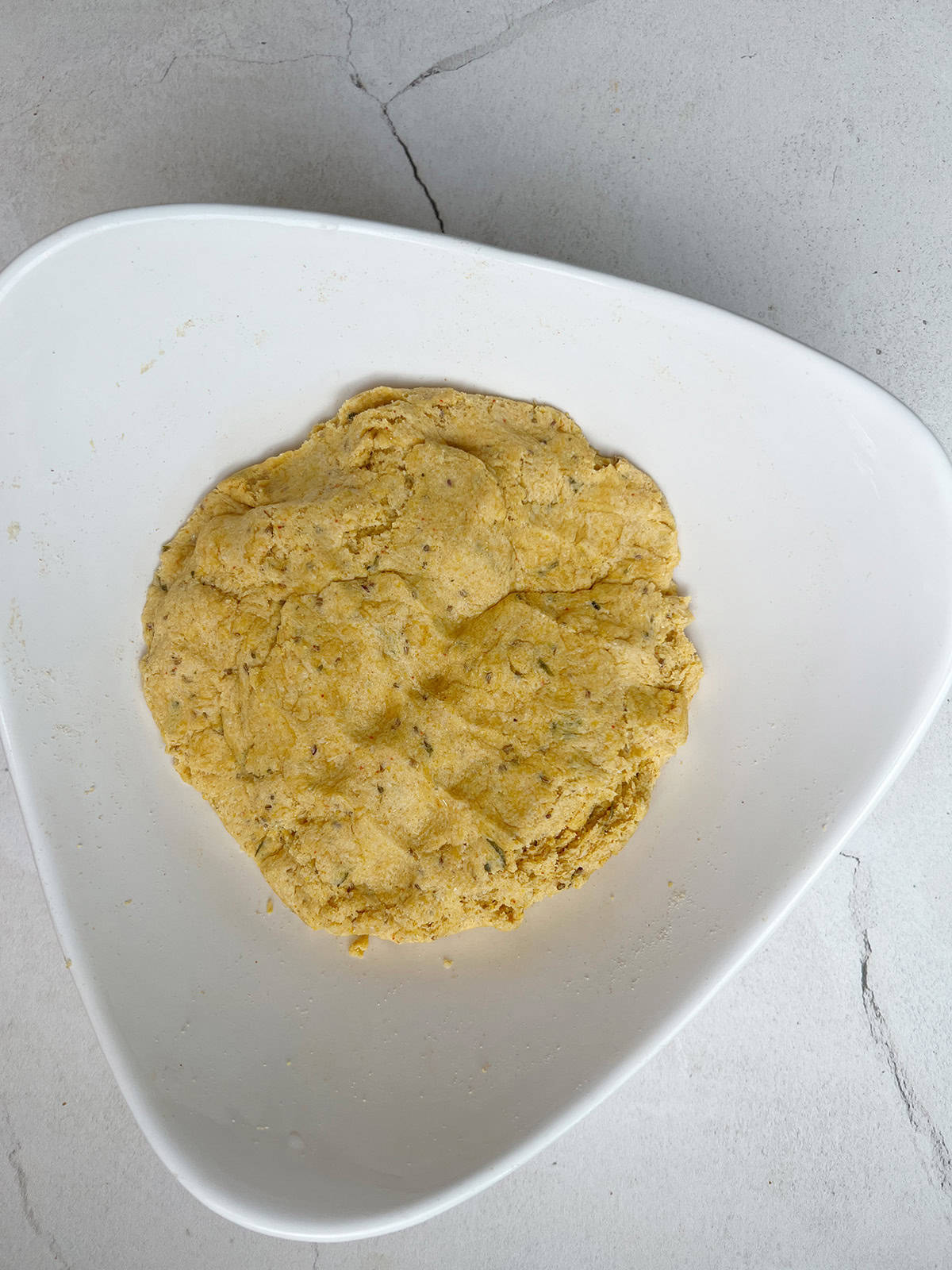 freshly kneaded makki ki roti dough is in a white bowl.