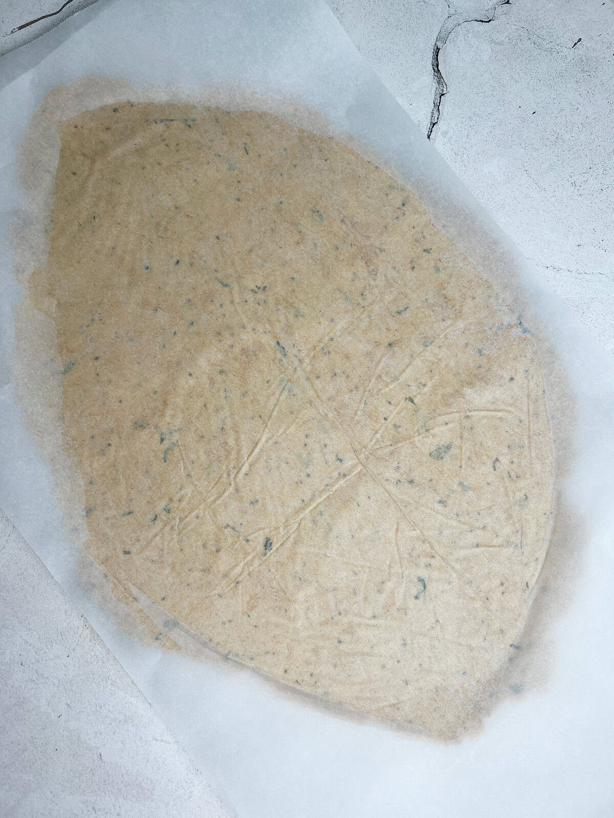 makki ki roti dough is rolled in between two sheets of parchment, ready for a tart recipe.