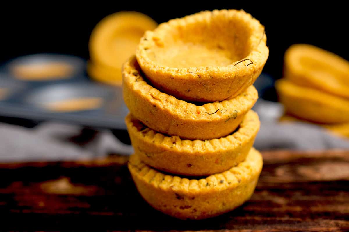 makki ki roti tarts made with a combination of cornmeal and atta are stacked on a dark wooden board.