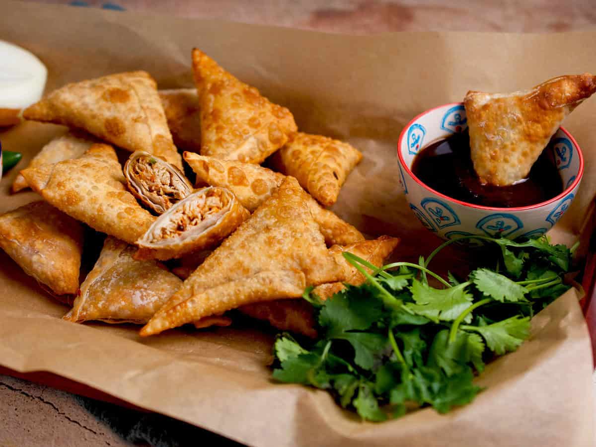 Chicken samosas with a bowl of tamarind chutney on the side.