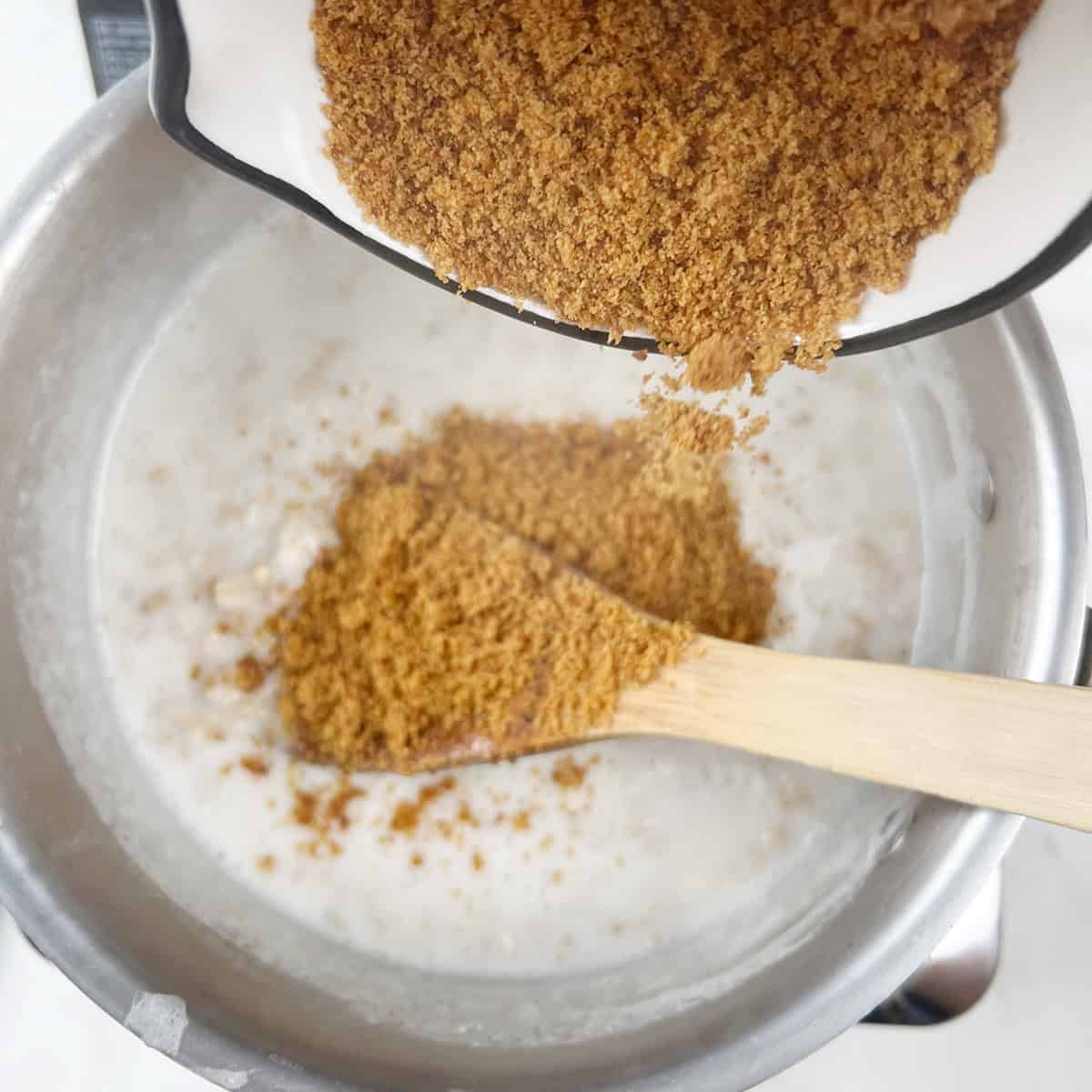 Jaggery is being added to a steaming pot of oatmeal.