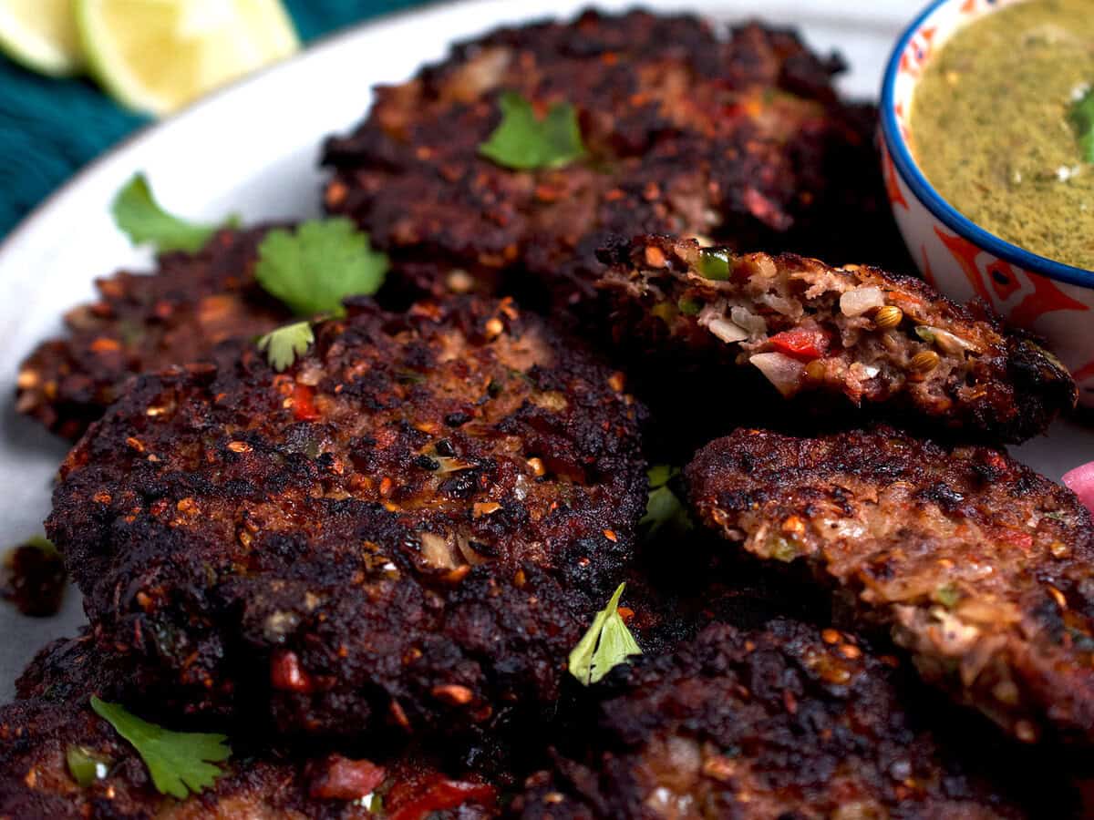 Chapli kabab with a bowl of chutney on the side.