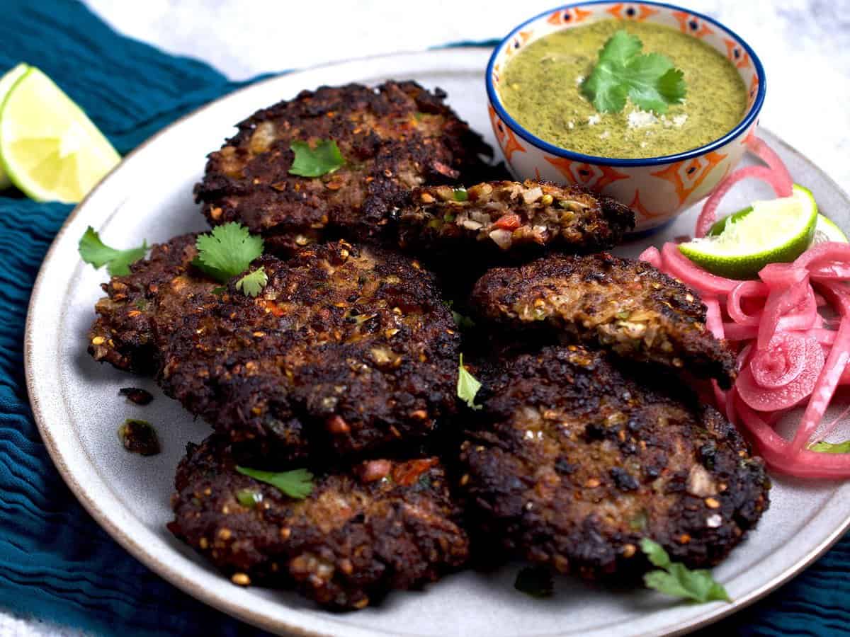 Chapli kabab with a side of chutney and pickled onions.