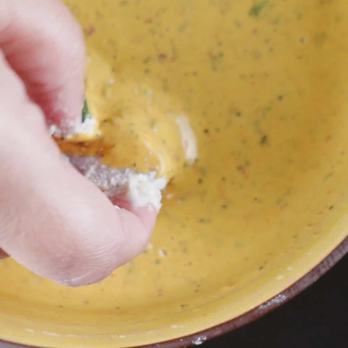 Fish coated in flour being dipped in a batter.