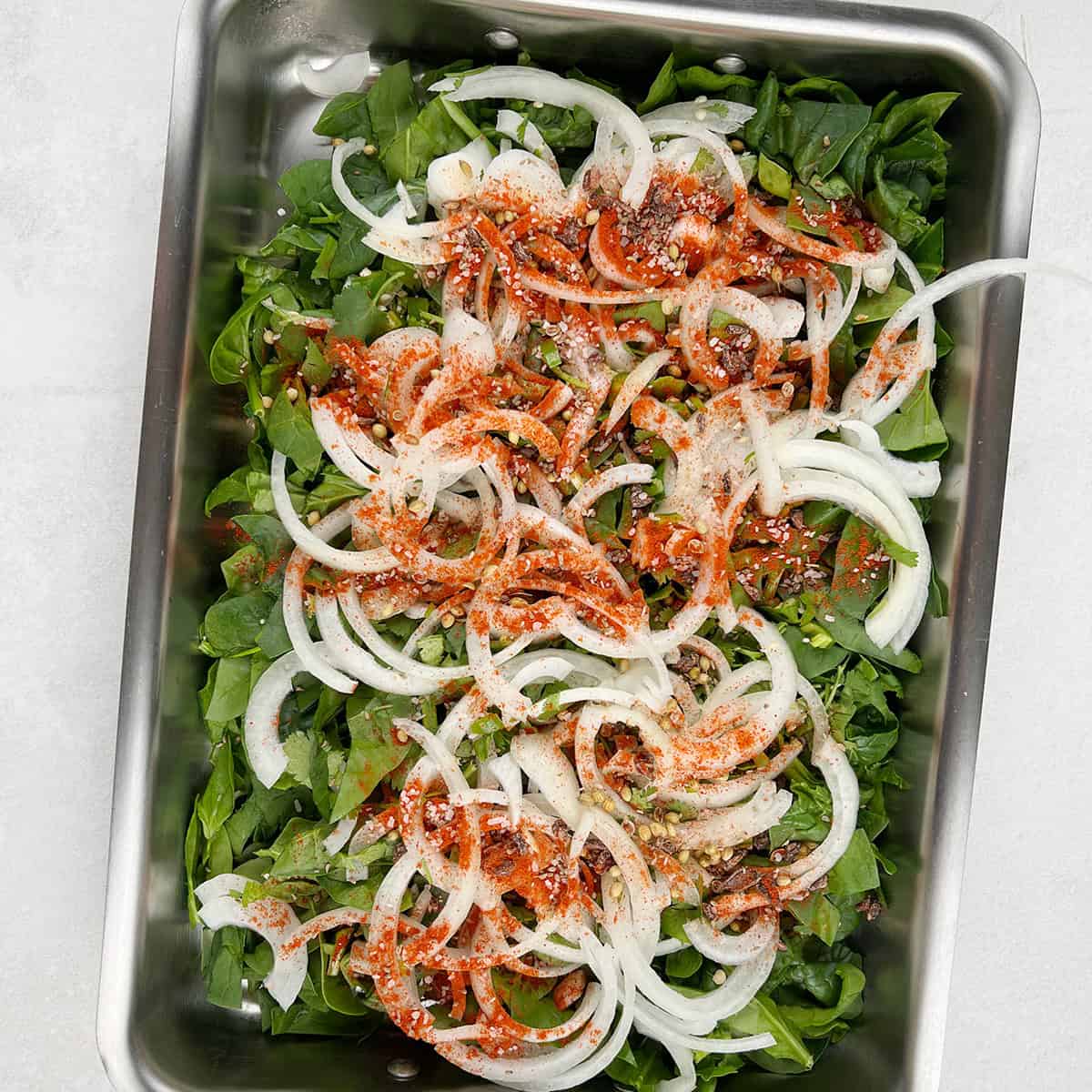 spinach and onions are being tossed in spices.