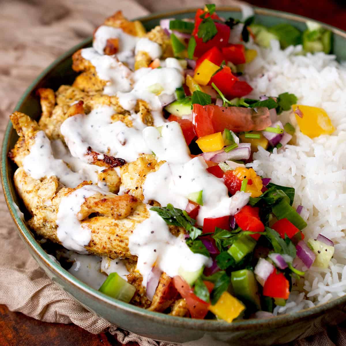 Chicken shawarma served with rice, vegetables and a creamy sauce.
