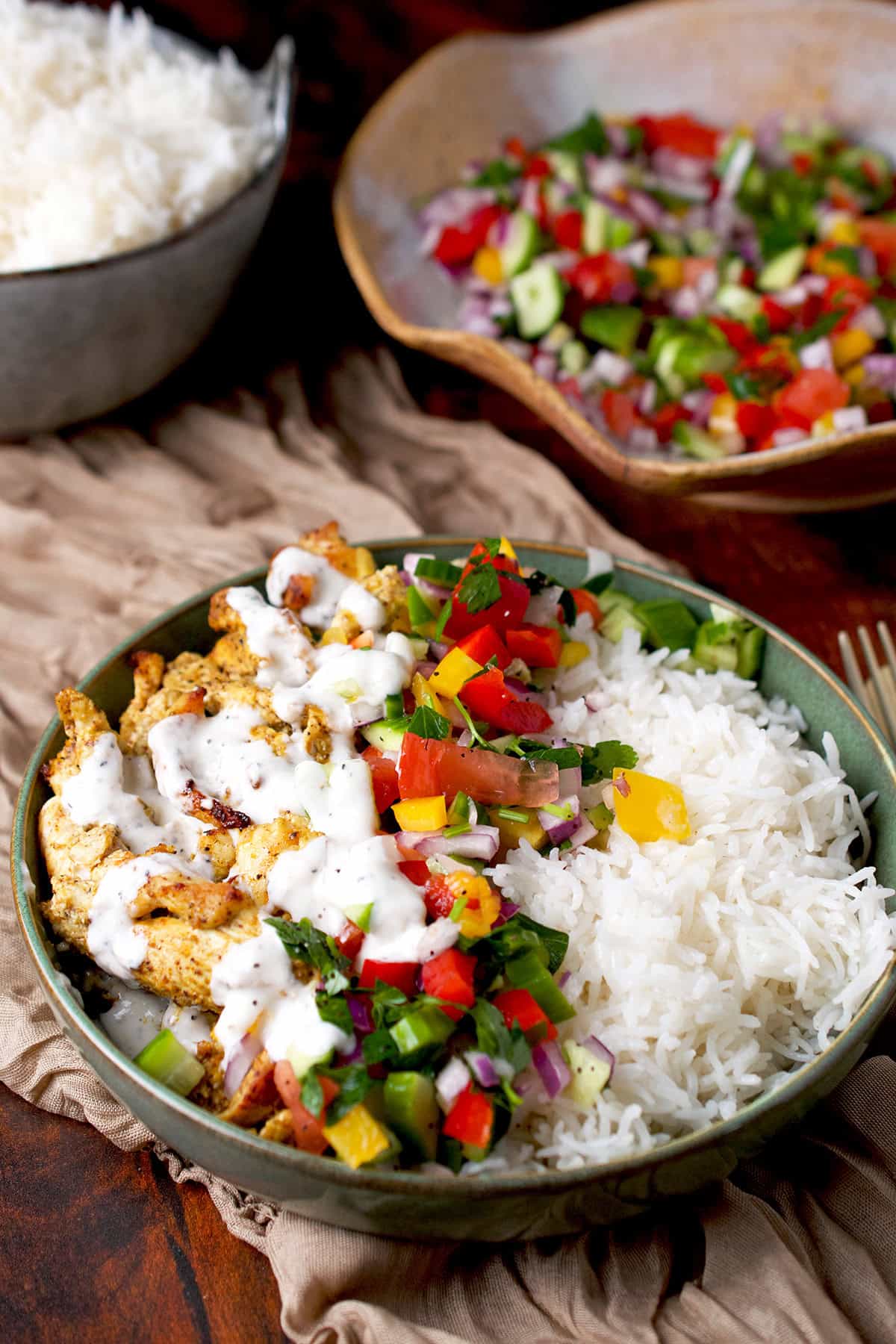 A chicken shawarma bowl with rice and a chopped salad.