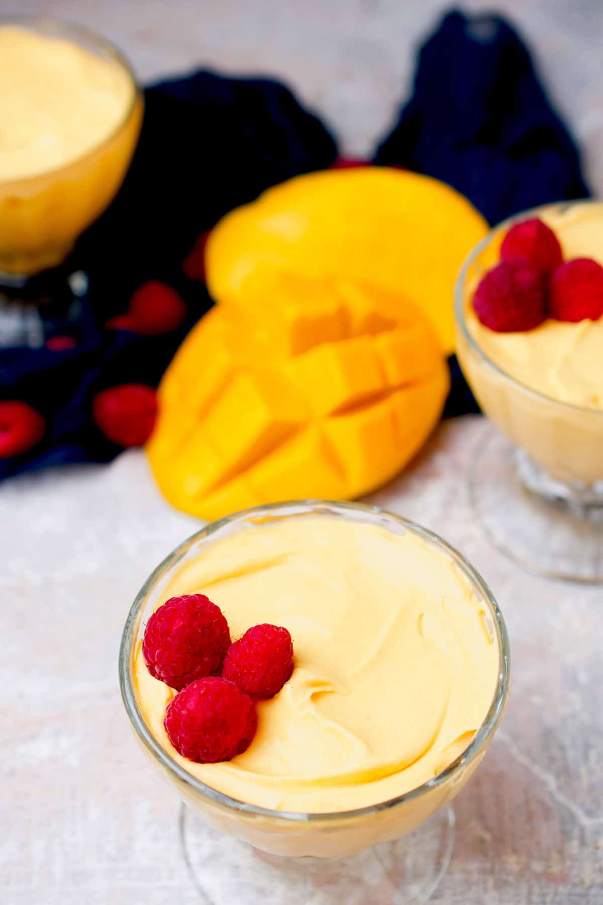Mango mousse dessert cup with a raspberry garnish.